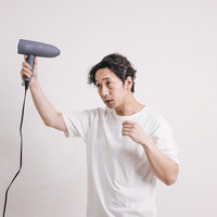 ドライヤーで髪をセットするヘアケア中の男性の写真