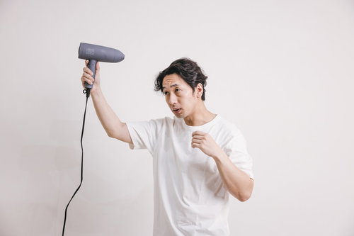 ドライヤーでブローをしながら頭皮をチェックするアラフォー男性