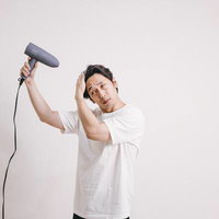 ドライヤーを使って髪をブローする男性のヘアスタイリングの写真