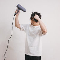 ドライヤーで髪をブローしてヘアセットする男性の写真
