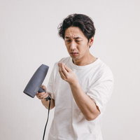 ドライヤーでブローしながら抜け毛を気にする中年男性の写真