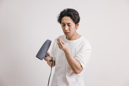 ドライヤーでブローしながら抜け毛を気にする中年男性