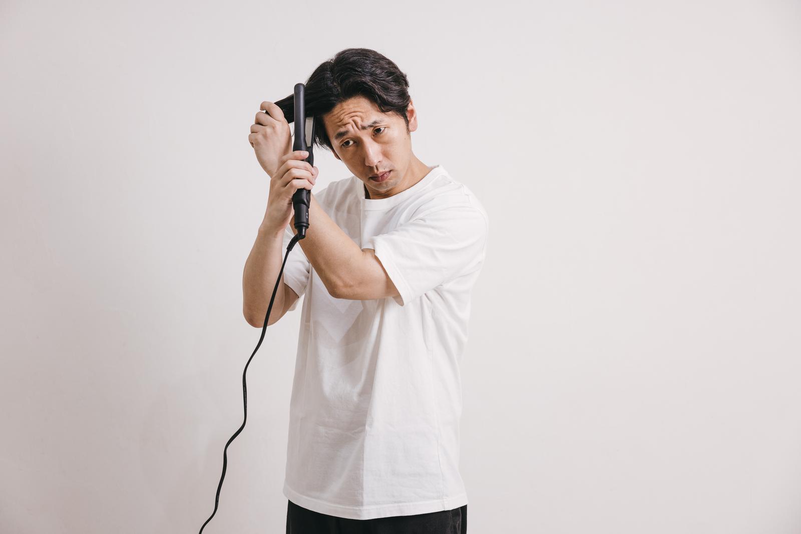 ヘアアイロンで髪をセットする男性［モデル：大川竜弥］