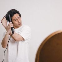 鏡の前でヘアアイロンを使ってセットする男性の写真