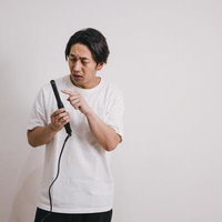 ヘアアイロンの高温部分に指を近づける男性の写真