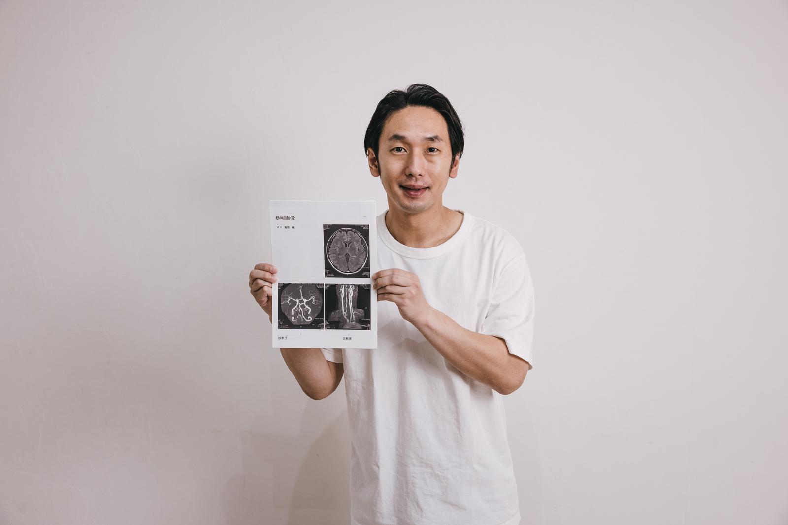 健康診断で脳ドッグのMRI画像をタブレットで見せる男性［モデル：大川竜弥］