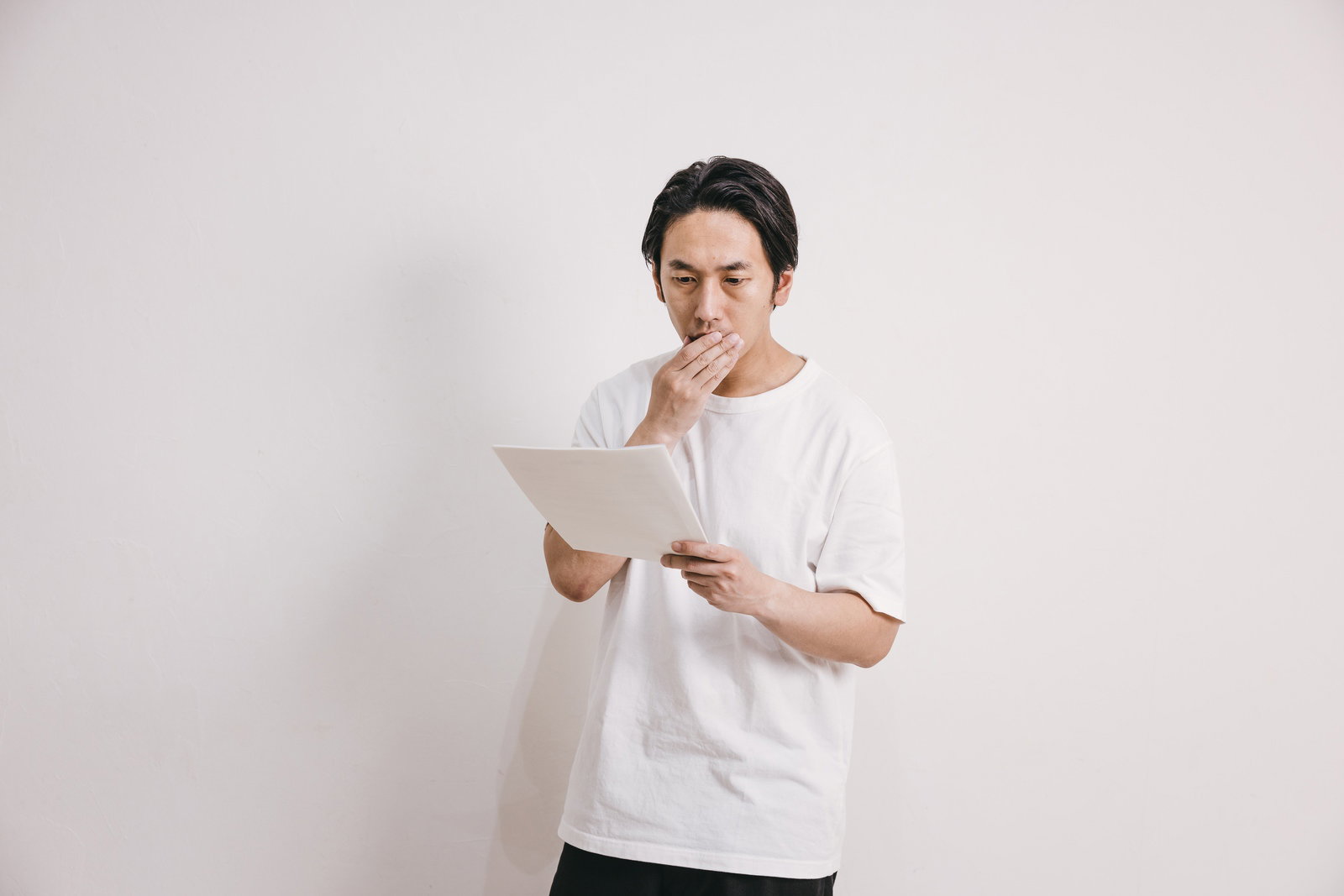 健康診断の結果を見て驚いている白い服の男性［モデル：大川竜弥］