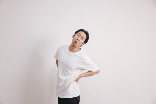 腰を押さえて痛みを訴えるぎっくり腰の男性