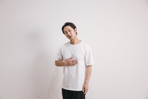 消化不良で胃が痛む男性（室内）