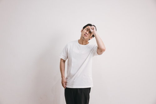 発熱で体調不良を感じ頭を押さえる男性の頭痛