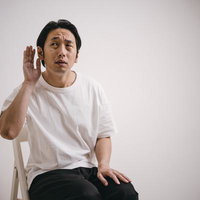 内緒話に聞き耳をたてる男性の仕草の写真