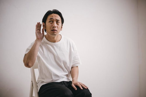 内緒話に聞き耳をたてる男性の仕草