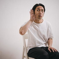 聞き耳を立てているフリをする白いシャツの男性の写真