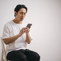 スマホでお祈りメール連発する無職男性が室内で座るの写真