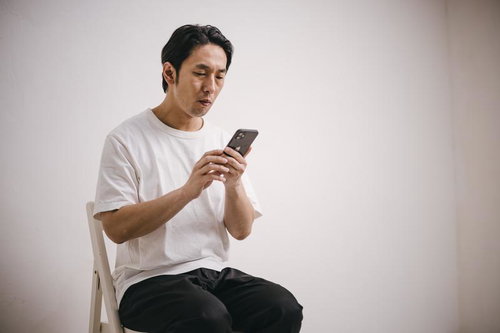 スマホでお祈りメール連発する無職男性が室内で座る