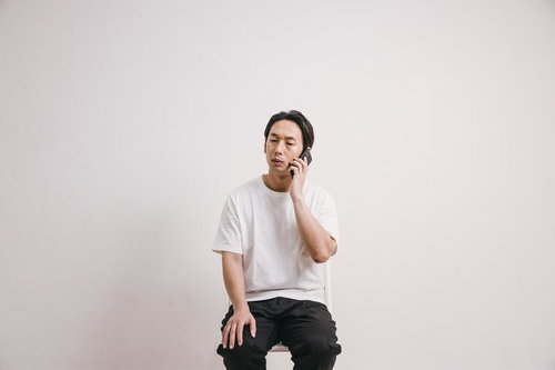 電話で言い訳を考える困った表情の男性のスマホ通話シーン