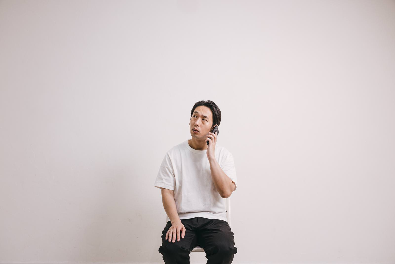 白いTシャツを着た男性が携帯電話で通話している［モデル：大川竜弥］