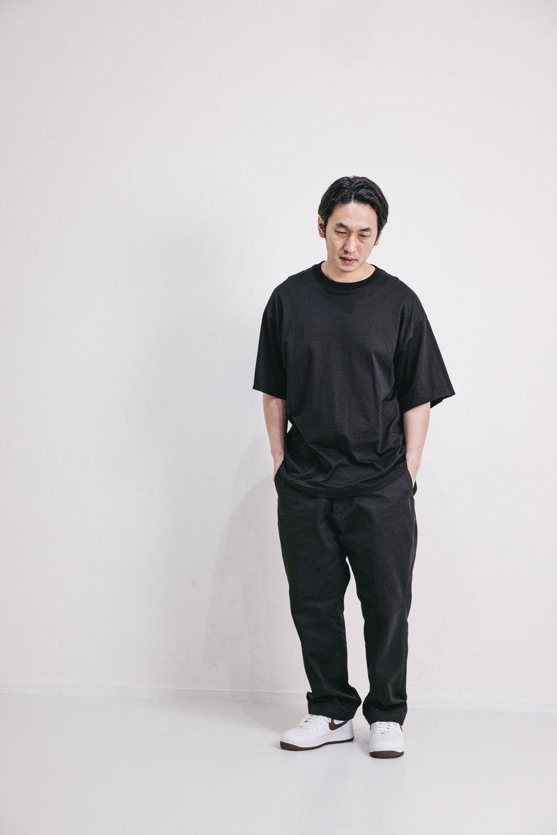 黒い服を着てうつむく男性の全身写真［モデル：大川竜弥］