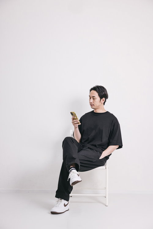 新品のスニーカーをはいて椅子に座りスマホを操作する男性