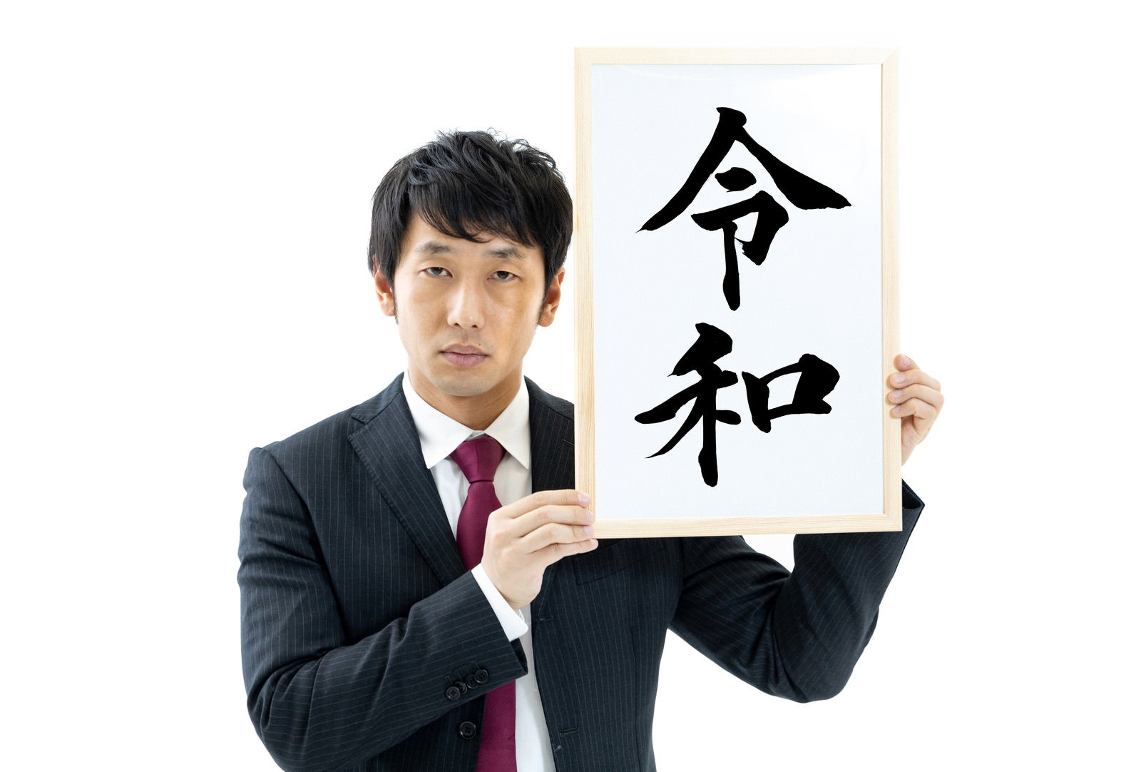 スーツ姿の男性が「令和」と書かれた白い紙を両手で掲げている［モデル：大川竜弥］