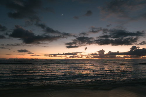 日が沈む海岸に染まる夕焼け、波打ち際に映る太陽の光