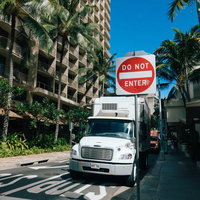 ハワイの歩道脇に停車する大型トレーラーと赤い道路標識の写真