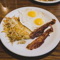 ザ・アメリカンなブレックファースト、白いプレートに盛られたベーコンと卵焼きの写真