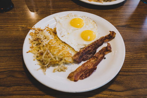 ザ・アメリカンなブレックファースト、白いプレートに盛られたベーコンと卵焼き