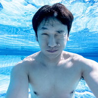 プールで潜りながら自撮りをする男性の水中の写真