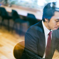 コワーキングスペースで集中して仕事をするスーツの男性の写真
