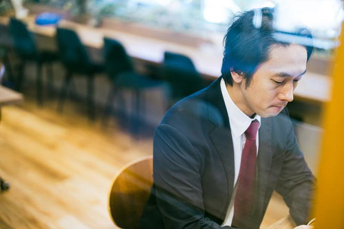 コワーキングスペースで集中して仕事をするスーツの男性