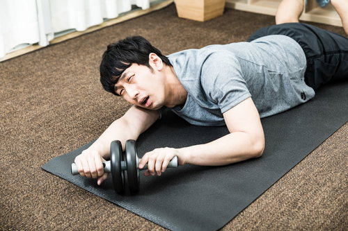 幸福のCDをBGMに腹筋ローラーで筋トレを頑張る男性