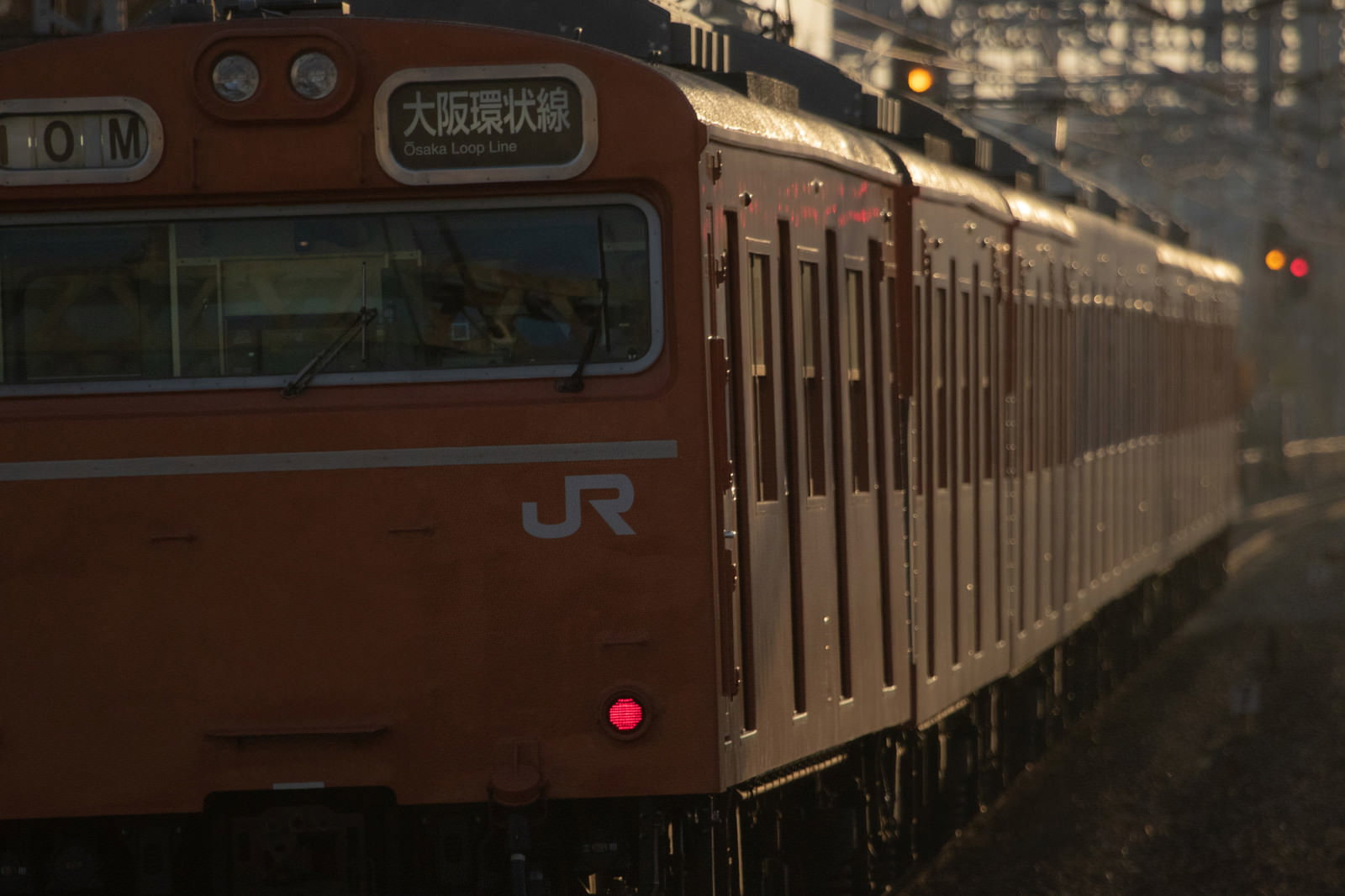 夕暮れ時の線路を走行する大阪環状線103系電車のオレンジ色の車両