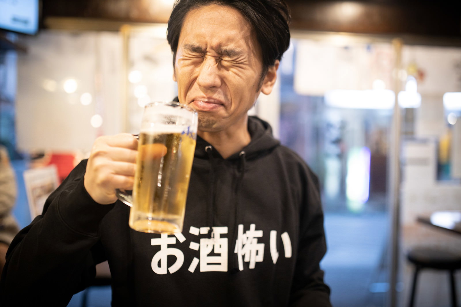 居酒屋でビールジョッキを持ってほろ酔い気分の中年男性［モデル：大川竜弥］