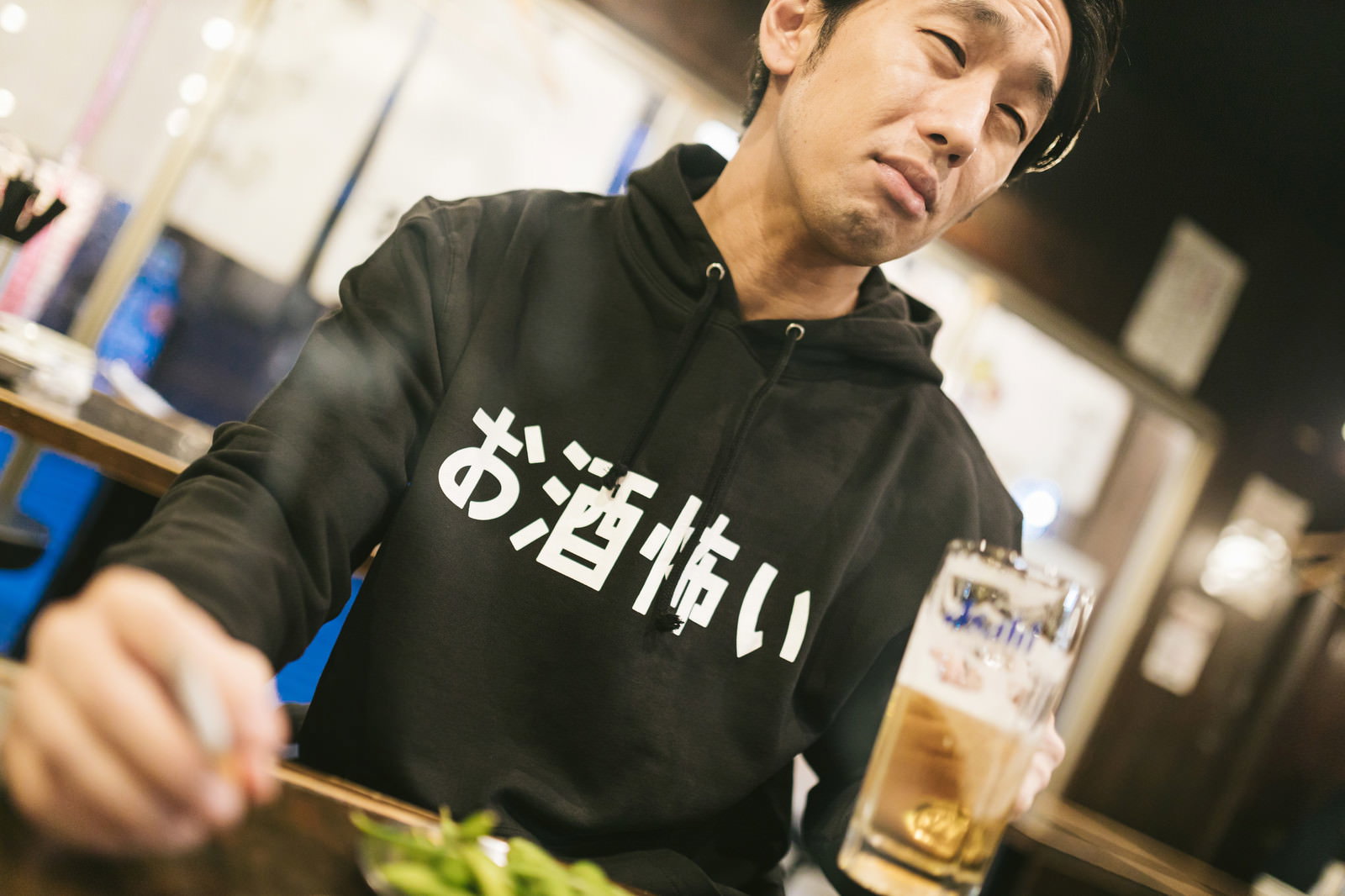 居酒屋でビールを飲みながらタバコを吸う男性［モデル：大川竜弥］