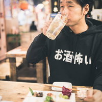 居酒屋で深夜まで飲み続けるハイボールを手にした男性の写真