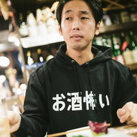 お酒怖いと書かれたパーカーを着てハイボールを飲む男性の写真
