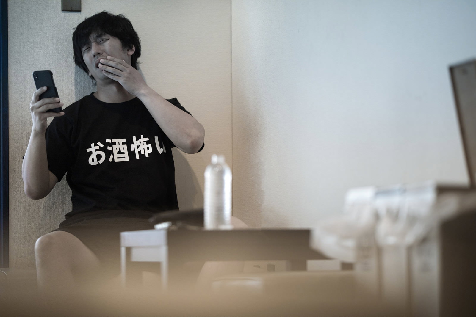 黒いTシャツを着た男性が手で口元を覆い困った表情をしている様子［モデル：大川竜弥］