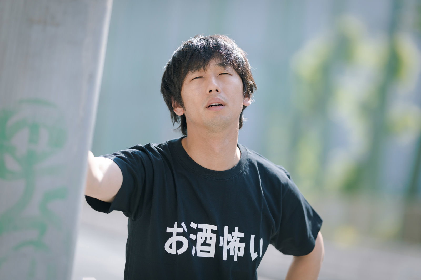 黒いTシャツを着て疲れた表情で上を見上げる男性［モデル：大川竜弥］