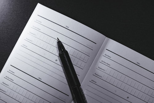 パスワード管理帳をペンで記入する手元