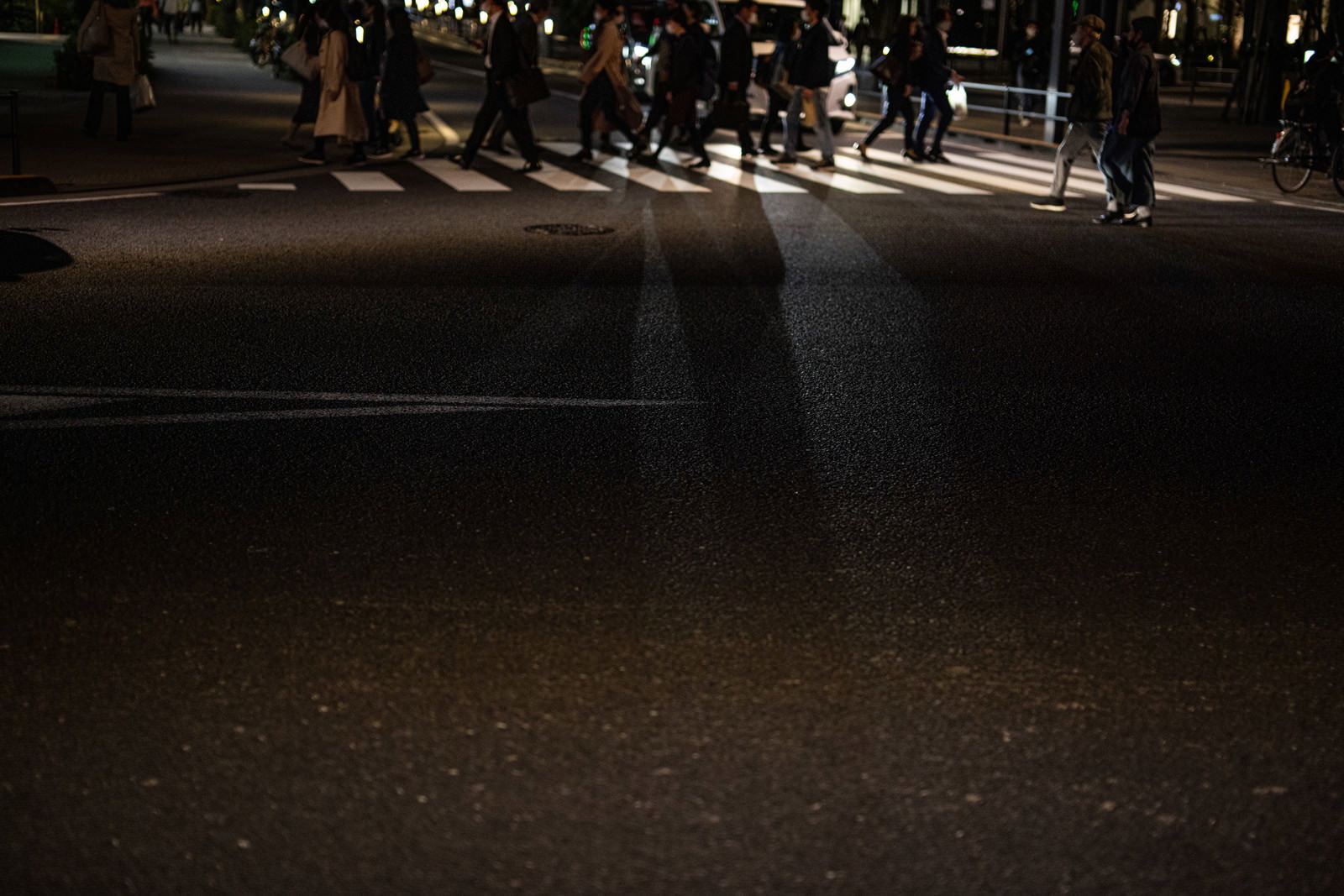 夜の街で横断歩道を渡る複数の人々のシルエット