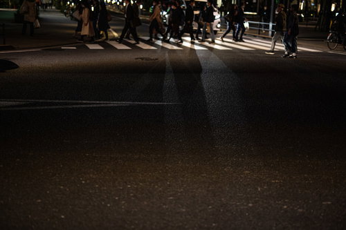 夜道の横断歩道を渡り帰路に就く人々と街灯