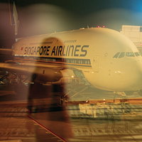 空港ターミナルの窓に映る女性の影と駐機する飛行機の写真