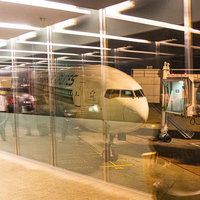 空港ターミナルのガラスに映り込む旅行者と旅客機の写真