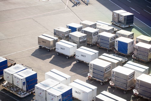 空港の滑走路に整然と並ぶ航空貨物コンテナ