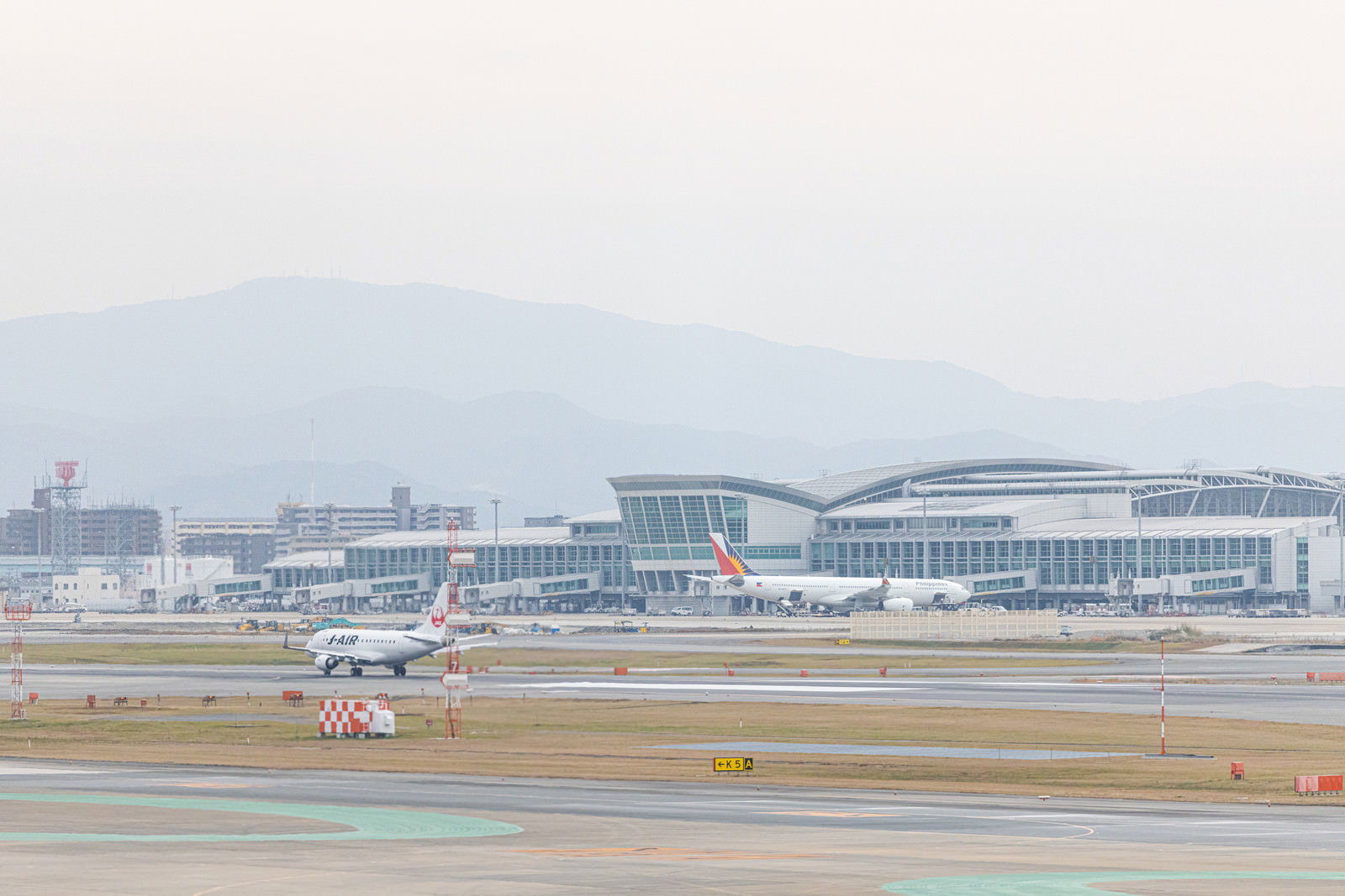 福岡空港の滑走路に駐機する複数の旅客機とターミナルビル