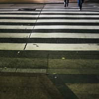 横断歩道を歩く足元、白と黒のゼブラ模様の歩行者の写真