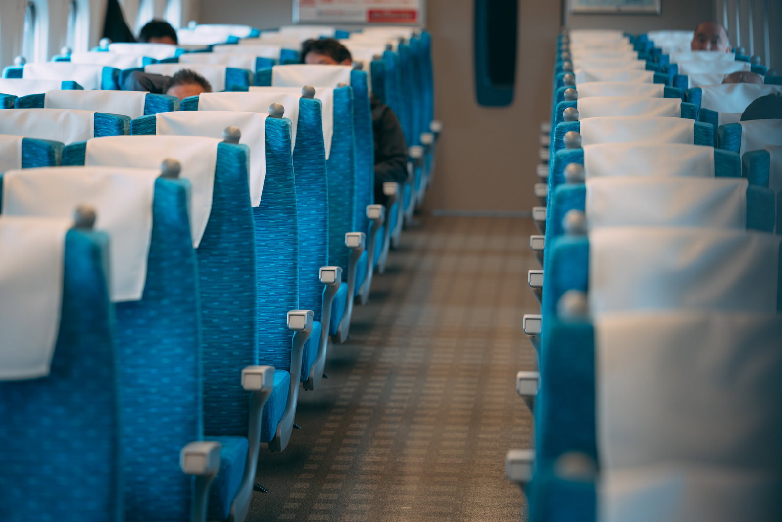 青いシート座席が並ぶ新幹線の車内。多くの座席が空いている