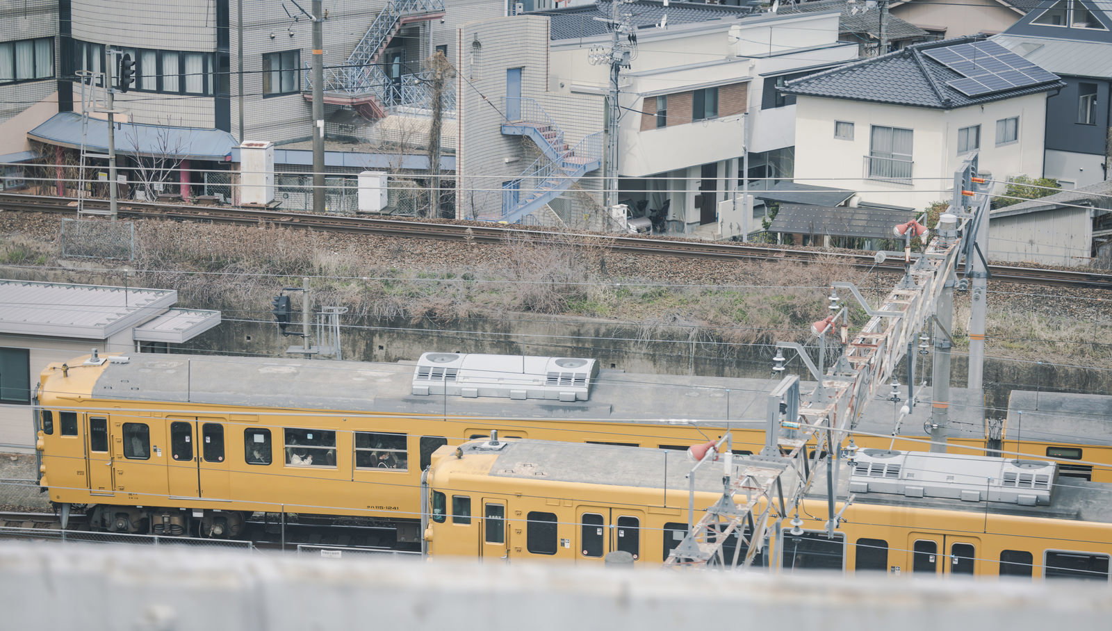山陽本線の駅に停車する黄色いクハ115形電車