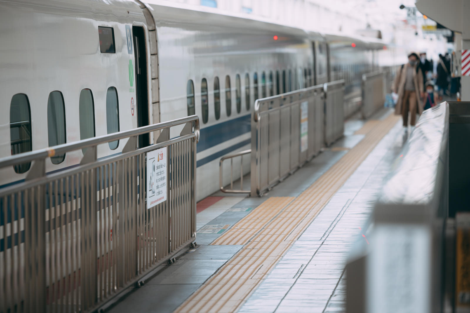 新幹線が停車する駅のホームに乗客が立っている風景